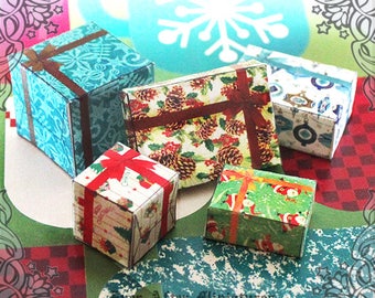 Può includere: Cinque scatole regalo in miniatura avvolte in carta festiva. Le scatole sono decorate con vari motivi, tra cui pigne, fiocchi di neve e un nastro rosso. Le scatole sono disposte su una superficie a motivi.
