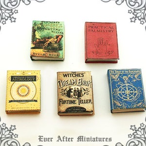May include: Five miniature books with vintage covers. The books are titled "Fontaine's Golden Witch Fortune Teller", "Practical Palmistry", "Complete Book of Predictive Astrology", "The Witches Dream Book Fortune Teller", and "The Tarot of the Bohemians".
