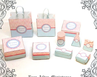 Könnte beinhalten: Ein Set aus Miniaturboxen und -taschen in einem rosa-blauen Farbschema. Die Boxen und Taschen haben ein kreisförmiges Design mit dem Text "Ever After" in der Mitte. Das Set umfasst verschiedene Formen und Größen, darunter einen hohen Zylinder, eine Pyramide und eine rechteckige Box.