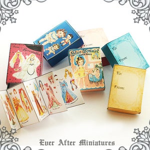 May include: A set of vintage paper doll boxes with a blue and white color scheme. The boxes feature illustrations of children in dresses and include the text "Blue Bonnet Paper Dolls".