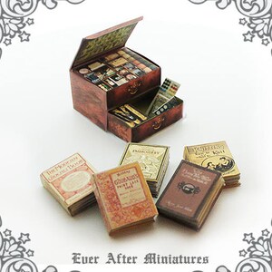 Puede incluir: Un mostrador de tienda de madera en miniatura con cajones llenos de suministros de artesan&iacute;a en miniatura y libros. Los libros tienen t&iacute;tulos como "The Modern Crochet Book", "Embroidery", "Knitting", "Gourmet Paint Sock Yarn" y "The Magic of Knitting".