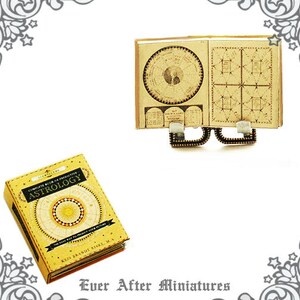May include: A miniature book titled "Complete Book of Predictive Astrology" with a yellow cover and gold accents. The book is open to a page with a circular chart and a grid pattern. The book is on a miniature stand with a gold finish.