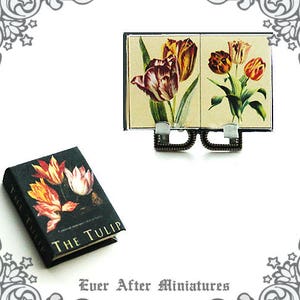 May include: A miniature book titled "The Tulip" with a black cover and colorful tulip illustrations. The book is displayed on a miniature easel with a vintage-style print of tulips.