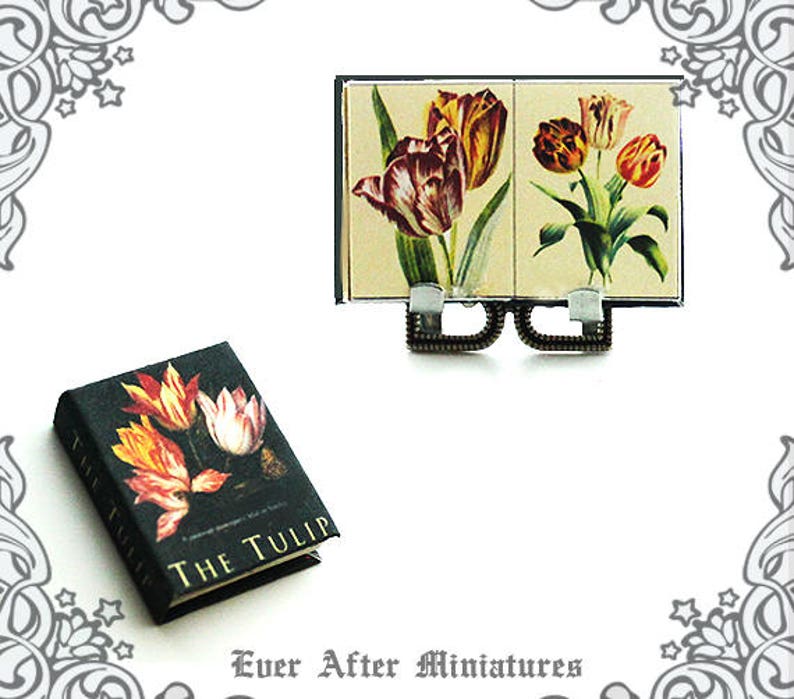 May include: A miniature book titled "The Tulip" with a black cover and colorful tulip illustrations. The book is displayed on a miniature easel with a vintage-style print of tulips.