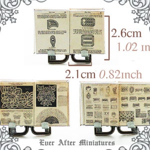 May include: Two miniature books with metal stands. The books are open and show pages of lace patterns. The books are 2.1 inches wide and 1.02 inches tall. The text on the pages reads "Pear Lace" and "Point Lace".
