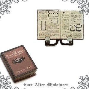 May include: A miniature book titled "The Dress You Wear And How to Make It" by Mary Jane Rhoe. The book is closed and has a brown cover with a sewing machine illustration. A miniature open book with sewing instructions is also pictured.