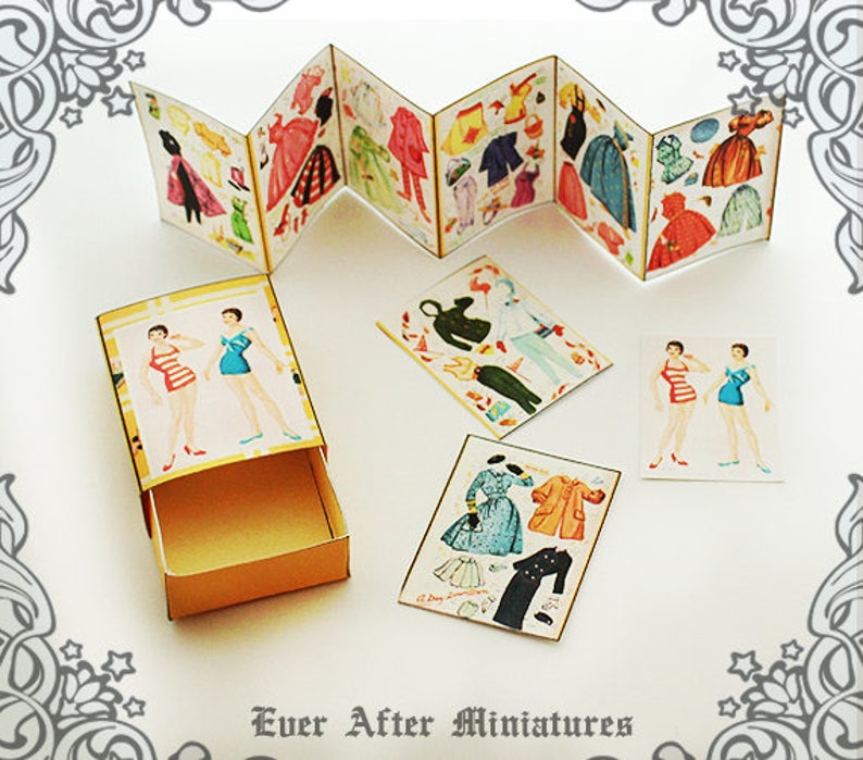 May include: A miniature paper doll set with a variety of outfits and accessories. The dolls are dressed in vintage-style clothing and have a charming, whimsical look. The set comes in a small box with a drawer for storage.