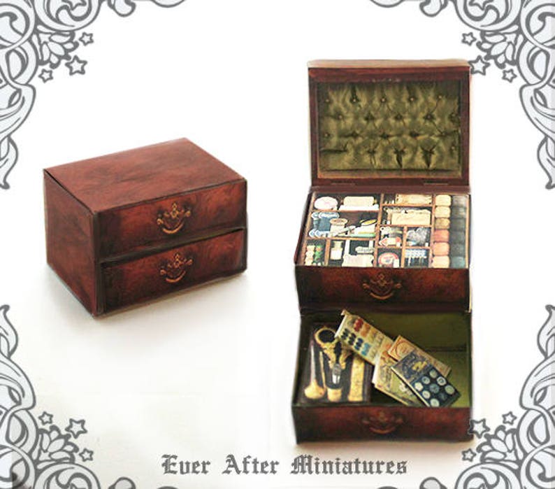 Puede incluir: Una caja de madera con dos cajones y una tapa con bisagras. La caja est&aacute; abierta y el interior est&aacute; lleno de peque&ntilde;os compartimentos y art&iacute;culos. La caja es marr&oacute;n con detalles dorados. El texto "Ever After Miniatures" est&aacute; impreso en la parte inferior de la imagen.
