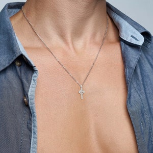 May include: A silver chain necklace with a small Celtic cross pendant.