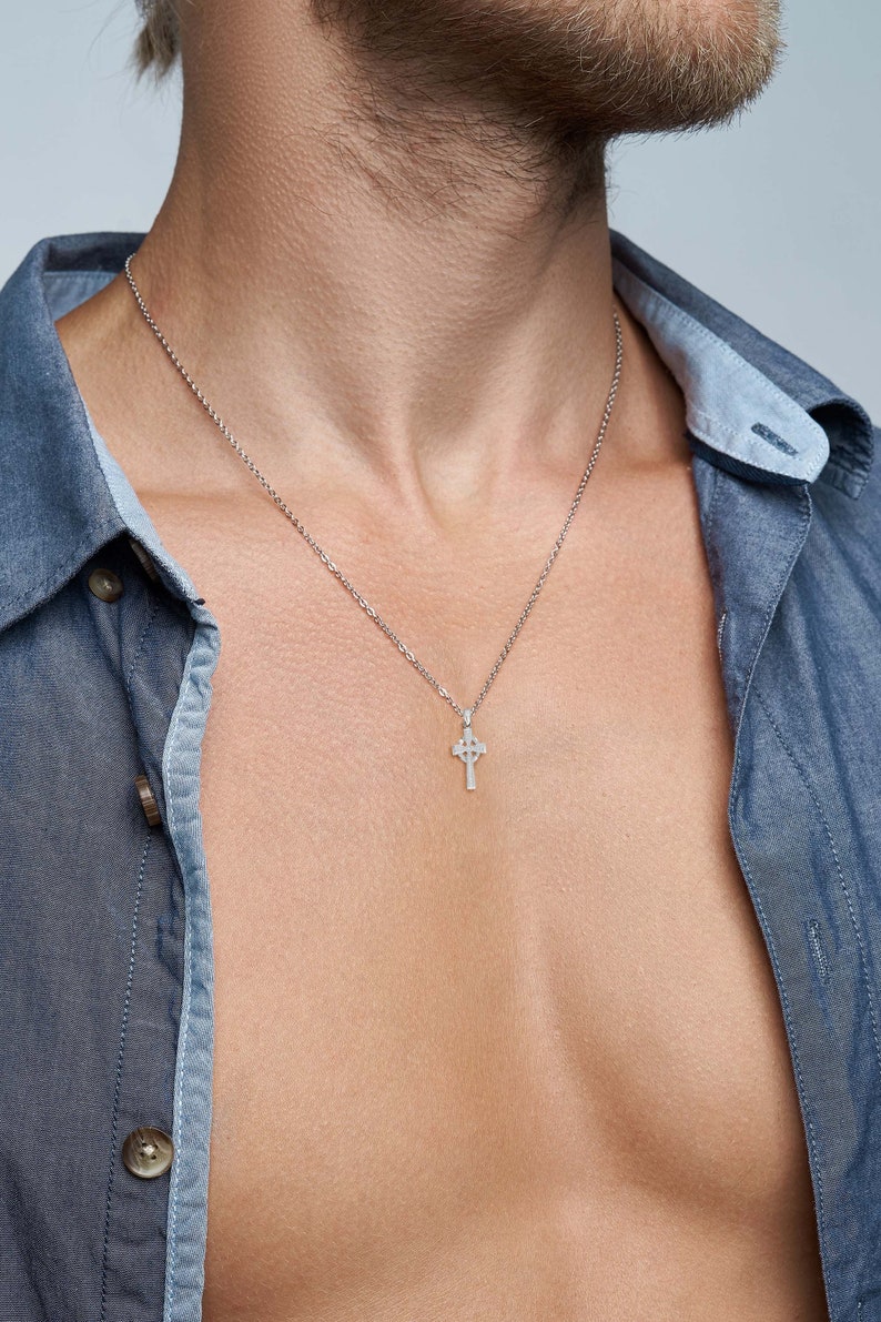May include: A silver chain necklace with a small Celtic cross pendant.