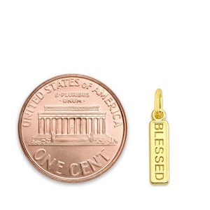May include: A gold-colored pendant charm with the word "BLESSED" engraved vertically. A U.S. one-cent coin is next to the charm for size comparison. The coin is copper-colored and shows the Lincoln Memorial.