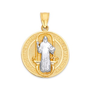 May include: A gold and silver pendant with a detailed design. The pendant is circular, with an image of a religious figure in the centre. The figure is silver, and the outer circle is gold. It has a loop at the top for a chain, suitable for a necklace.