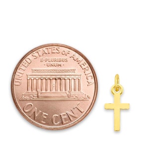 May include: A gold cross pendant charm, shown next to a US penny for size comparison. The cross is simple and elegant, with a smooth finish.