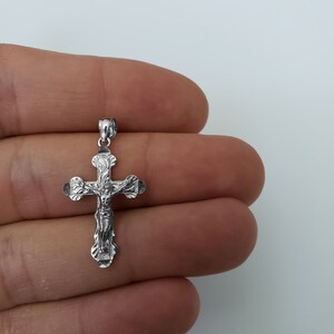 May include: A silver crucifix pendant with a detailed design of Jesus Christ on the cross.