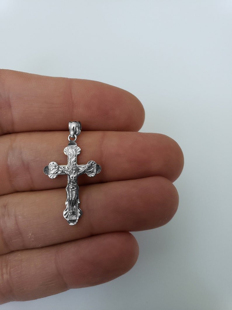 May include: A silver crucifix pendant with a detailed design of Jesus Christ on the cross.