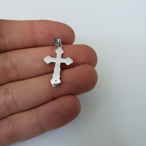 May include: Silver cross pendant with a detailed design. The cross has a smooth, polished finish.