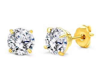 May include: A pair of gold stud earrings with a round, clear cubic zirconia stone in each earring.