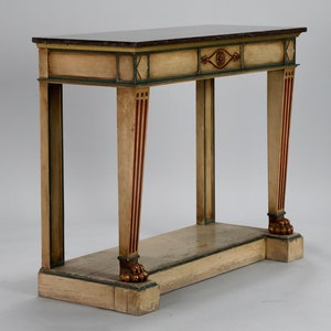 May include: A painted wooden console table with a dark brown top and a lower shelf. The table has a green and gold trim and red and gold accents on the legs. The legs are carved with lion's paws.