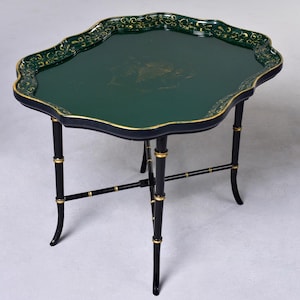 Op de afbeelding: Een decoratieve, donkergroene dienbladtafel met een geschulpte rand en zwarte poten in bamboestijl. De lade heeft gouden accenten langs de rand en op het oppervlak. De tafel is ongeveer 61 cm lang, 46 cm breed en 51 cm hoog.