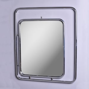 Puede incluir: Un espejo con marco de cromo y un diseño de doble marco. El espejo tiene forma cuadrada y una superficie reflectante.