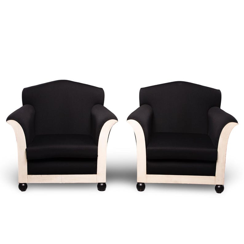May include: Two black armchairs with white trim and black legs. The armchairs are upholstered in a black fabric and have a classic design.