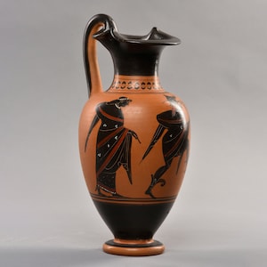 May include: Black-figure pottery vase with a red clay body and black painted figures. The vase has a tall, slender neck and a round body. The figures are of two people, one standing and one kneeling, with black and red details.