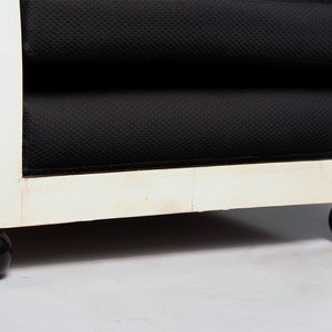 May include: Close-up of the bottom of a black and white armchair with black round legs.