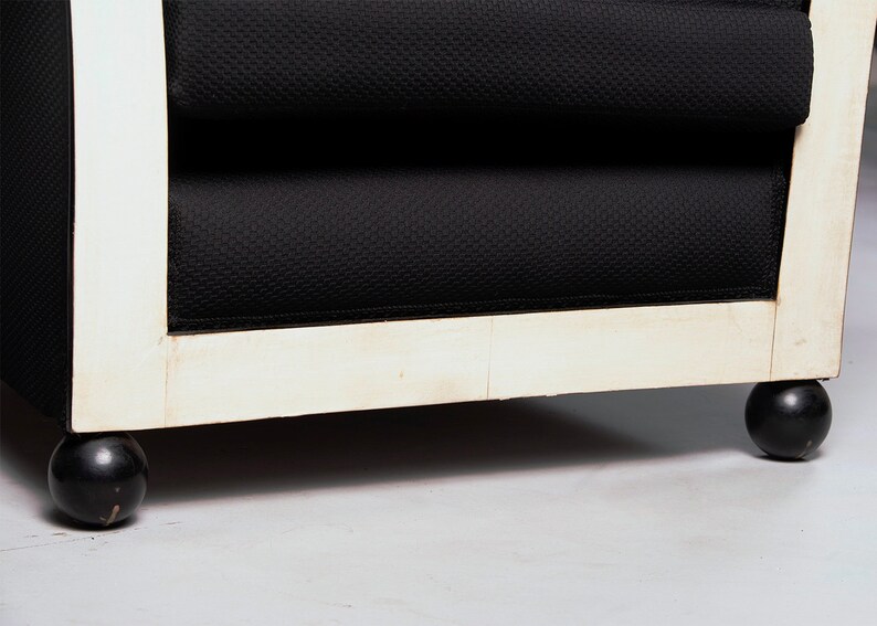 May include: Close-up of the bottom of a black and white armchair with black round legs.