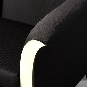 May include: Black armchair with a white curved armrest. The chair has a textured fabric upholstery.