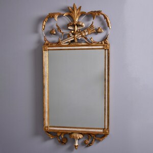 May include: A gold and white ornate mirror with a decorative top featuring a floral design and a central motif of a stylized fan. The mirror has a rectangular frame with a beveled edge.