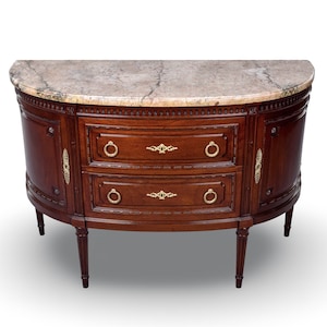 Può includere: Un tavolo console in legno a forma semicircolare con un piano in marmo lucido venato di grigio. La struttura in legno scuro presenta due cassetti centrali con maniglie ad anello dorate e decorazioni metalliche, su quattro gambe affusolate.