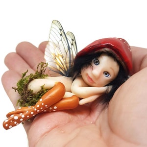 Blue-eyed forest fairy lying down. Decorative fairy figure made of cold porcelain elf, lying fairy elf