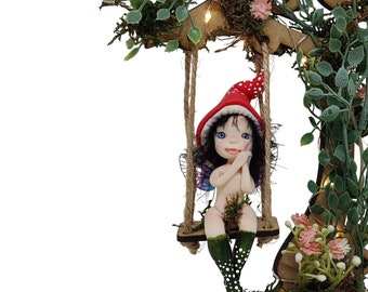 Forest fairy on swing. Decorative cold porcelain fairy figurine elf, miniature fairy elf, fairy garden