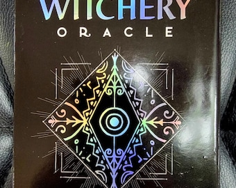 May include: A black oracle card deck titled "Sigil Witchery Oracle" by Laura Tempest Zakroff. The cover features holographic lettering and a geometric design with colorful accents. The text "60 Cards for Drawing Magic" is also visible.