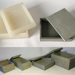 May include: A collection of rectangular concrete boxes with lids. Some boxes are open, revealing the interior. The boxes vary in size and color, with some appearing off-white and others gray. The lids are flat and fit snugly on the boxes.