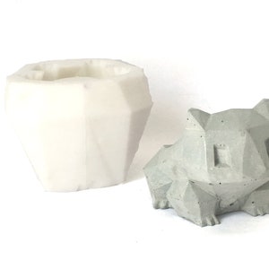 May include: A white silicone mould and a grey concrete planter shaped like a geometric animal. The planter has a geometric design and is perfect for small plants.