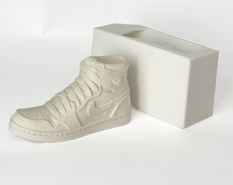 Könnte beinhalten: Eine weiße Silikonform zum Herstellen einer Sneaker-Replik. Die Form ist wie ein High-Top-Sneaker geformt mit einem sichtbaren Swoosh-Logo.