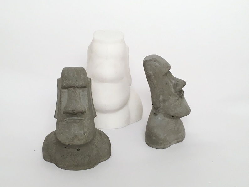 K&ouml;nnte beinhalten: Drei Betonstatuen von Osterinselk&ouml;pfen. Zwei der Statuen sind grau und eine ist wei&szlig;.