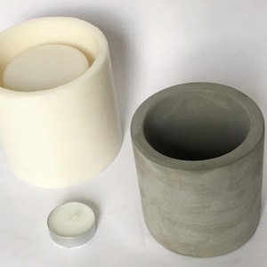 May include: Two cylindrical candle molds, one white and one gray, with a small white tea light candle.