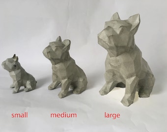 Könnte beinhalten: Drei Betonskulpturen eines französischen Bulldoggen in verschiedenen Größen: klein, mittel und groß. Die Skulpturen sind alle in hellgrauer Farbe gehalten und haben ein geometrisches, kantiges Design.