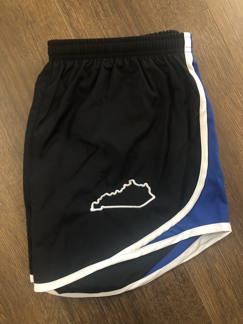 May include: Black running shorts with a white outline and blue trim. The shorts have a white outline of the state of Kentucky on the left side.
