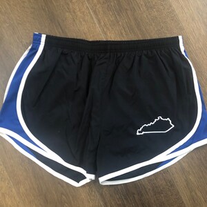 May include: Black running shorts with a white and blue trim. The shorts have a white outline of the state of Kentucky on the left side.