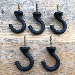 Op de afbeelding: Vijf zwarte metalen haken met een schroefdraad. De haken zijn allemaal even groot en even gevormd, en ze zijn in een rij gerangschikt.