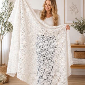 Op de afbeelding: Een crèmekleurige deken met open weefsel en een bloemmotief wordt getoond. De deken is gemaakt van een zacht materiaal en heeft een delicate, kantachtige uitstraling. De deken is ongeveer 178 cm breed en 203 cm lang.