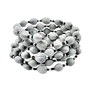 May include: A wrap bracelet featuring multiple strands of gray, oval-shaped beads. The beads are interspersed with smaller black and white beads, creating a contrasting pattern. The bracelet is designed to wrap around the wrist multiple times.