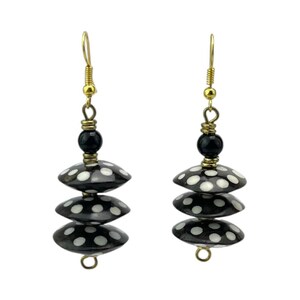 May include: A pair of black and white polka dot earrings with gold hooks. The earrings are made of three stacked round beads.