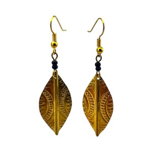 May include: A pair of gold-colored earrings with a leaf-like shape. The earrings have a decorative pattern and are suspended from gold-colored hooks with black beads. The earrings are designed to be worn as a fashion accessory.