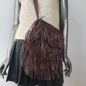 May include: A burgundy leather shoulder bag with long fringe details.