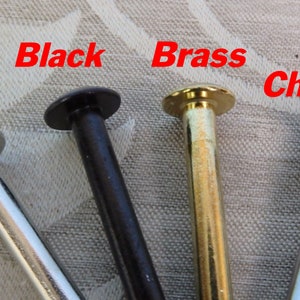 Op de afbeelding: Close-up van vier metalen klinknagels in verschillende afwerkingen: Mat Nikkel, Zwart, Messing en Chroom. Elke klinknagel heeft een afgeronde kop en een cilindrische steel. De namen van de afwerkingen staan in het rood erboven.