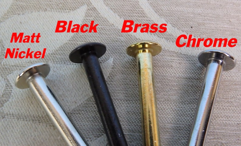Op de afbeelding: Close-up van vier metalen klinknagels in verschillende afwerkingen: Mat Nikkel, Zwart, Messing en Chroom. Elke klinknagel heeft een afgeronde kop en een cilindrische steel. De namen van de afwerkingen staan in het rood erboven.